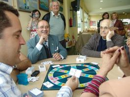 O ex alcalde Ram&oacute;n Rodr&iacute;guez Ares, con traxe e garavata, bot&aacute;ndolle unha partida ao trivial